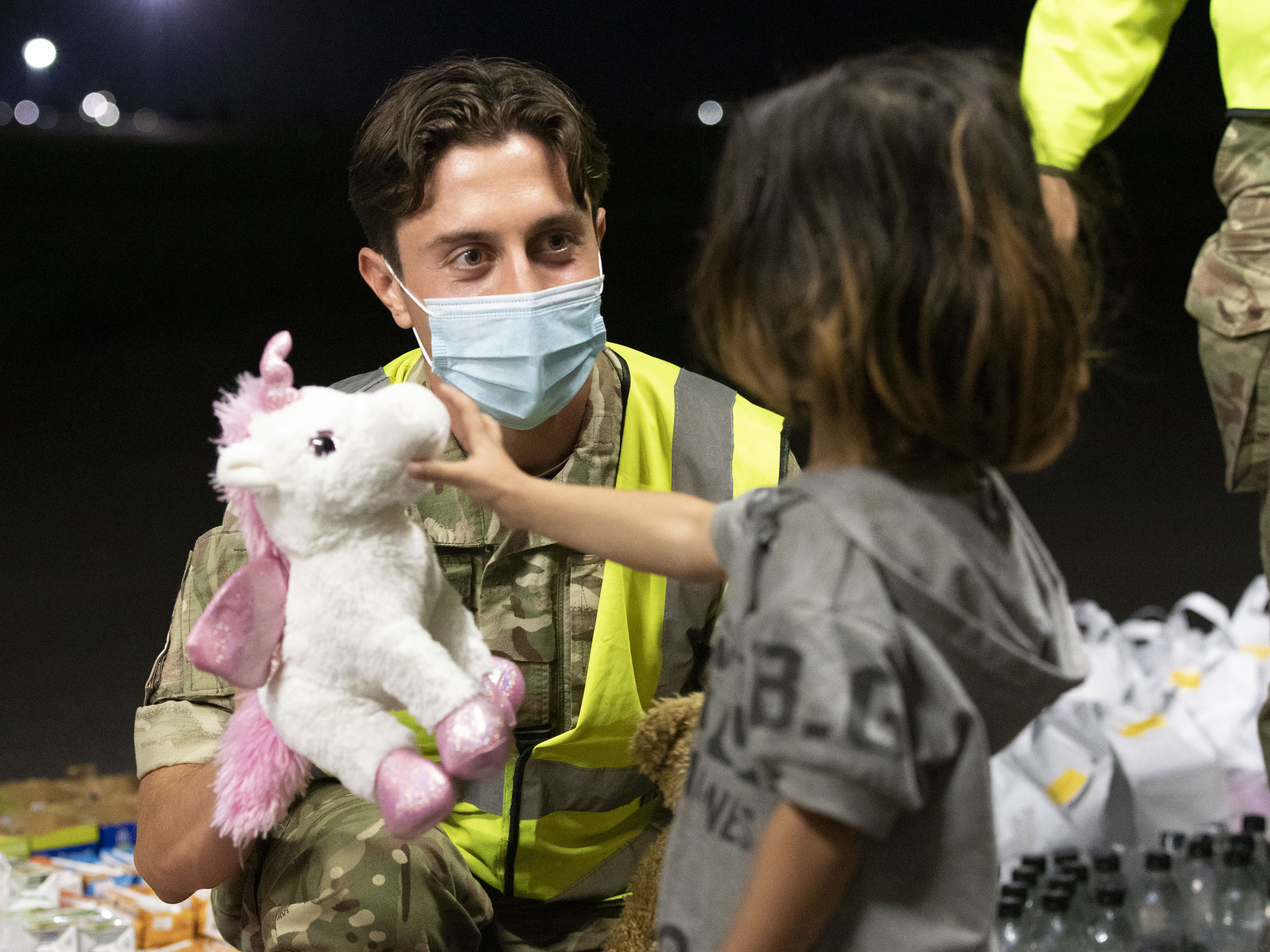 Personnel hand young child a toy unicorn.